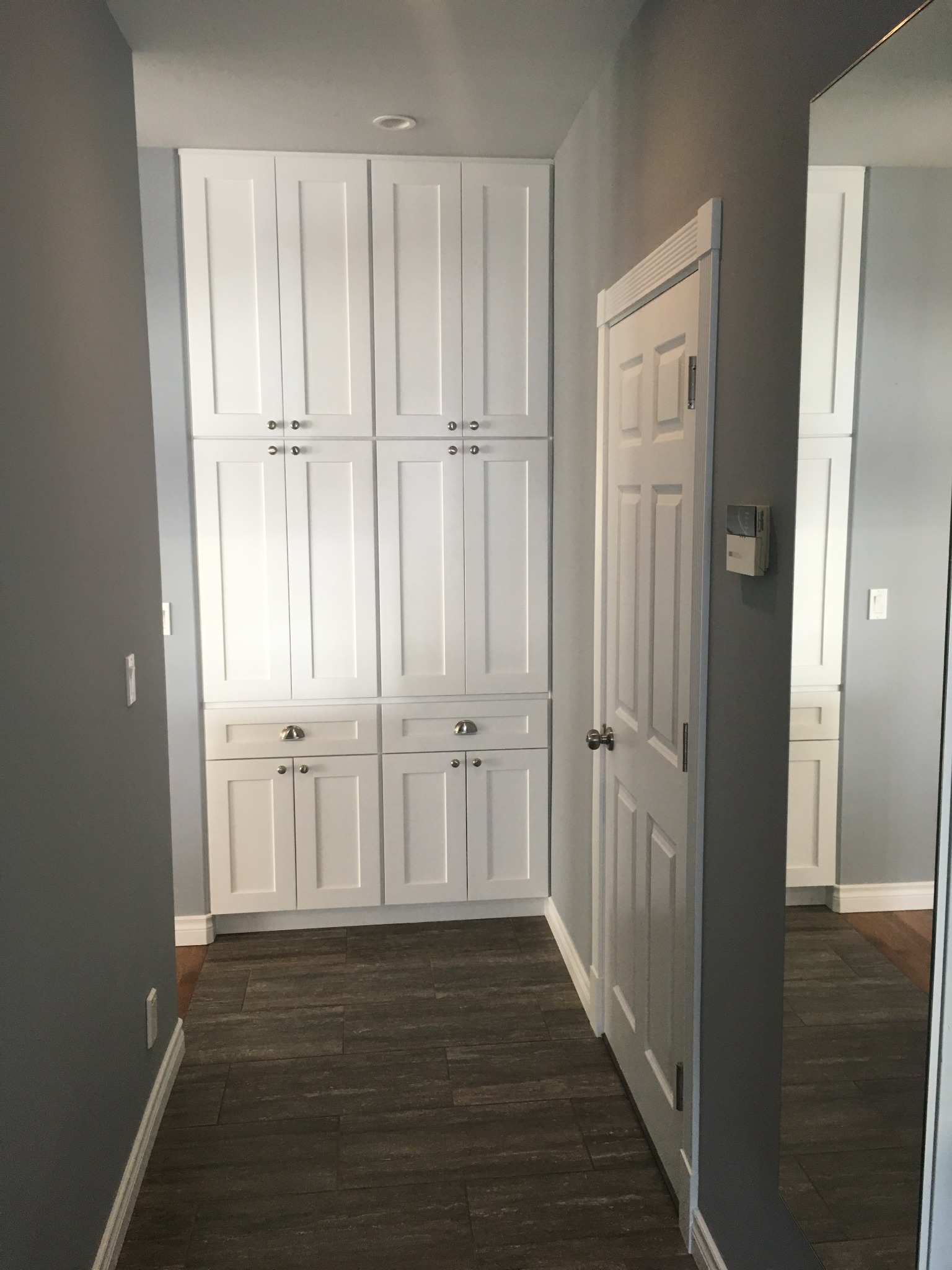 Built-in white hallway cabinets with dark wood flooring