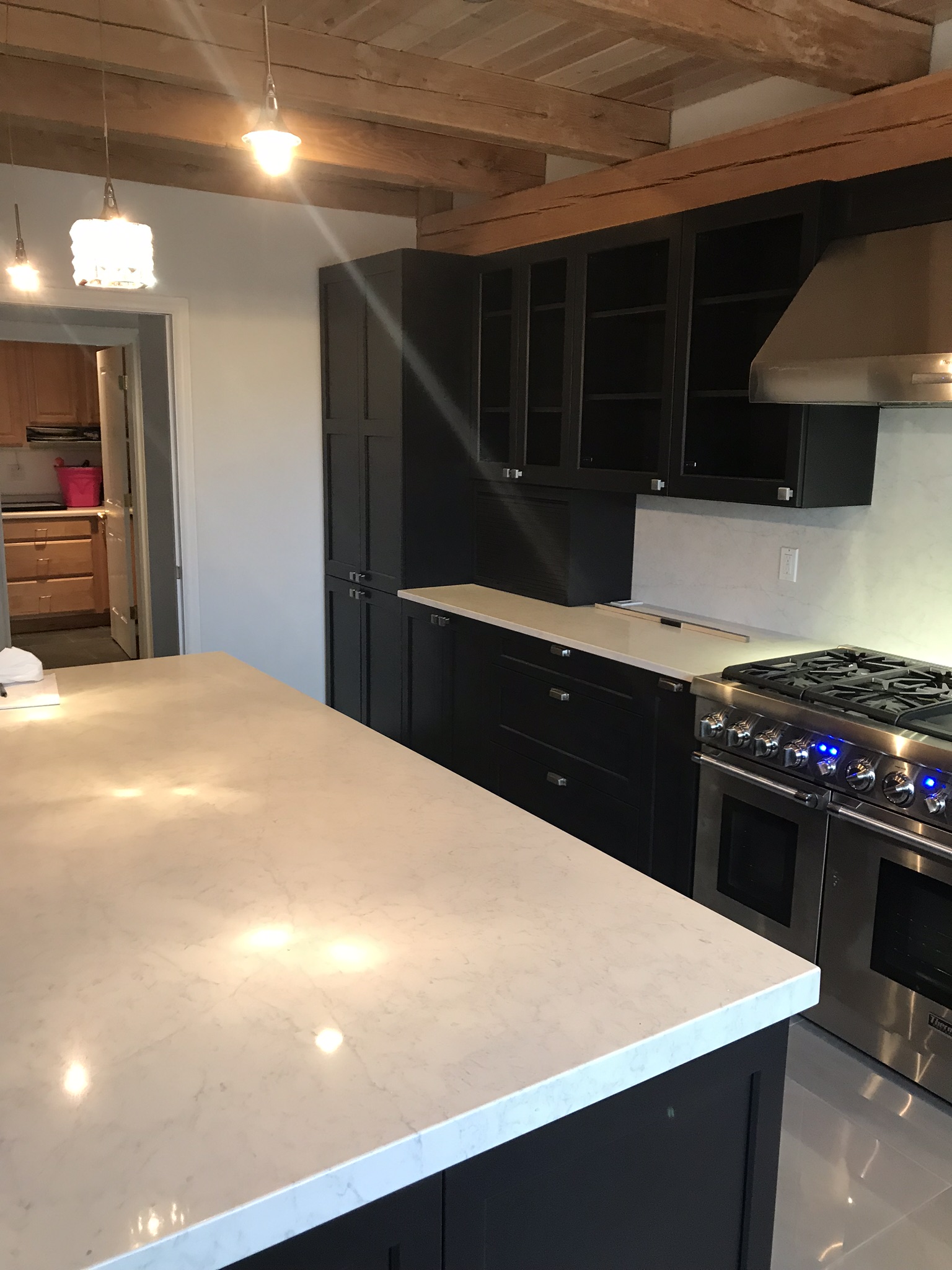 Black kitchen cabinets with commercial range, stainless hood, and light countertop