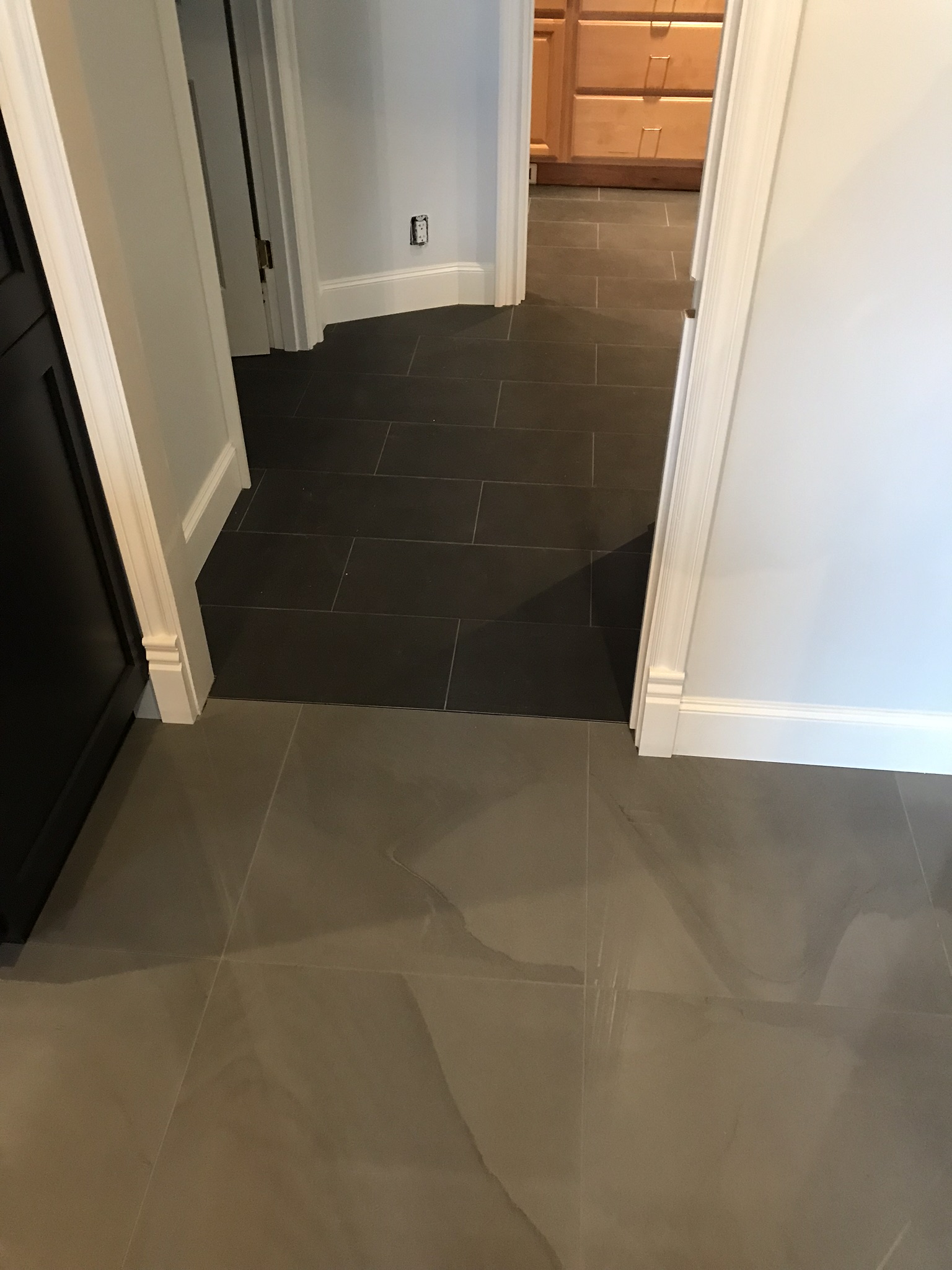 Large-format gray tile flooring installed through the kitchen entry
