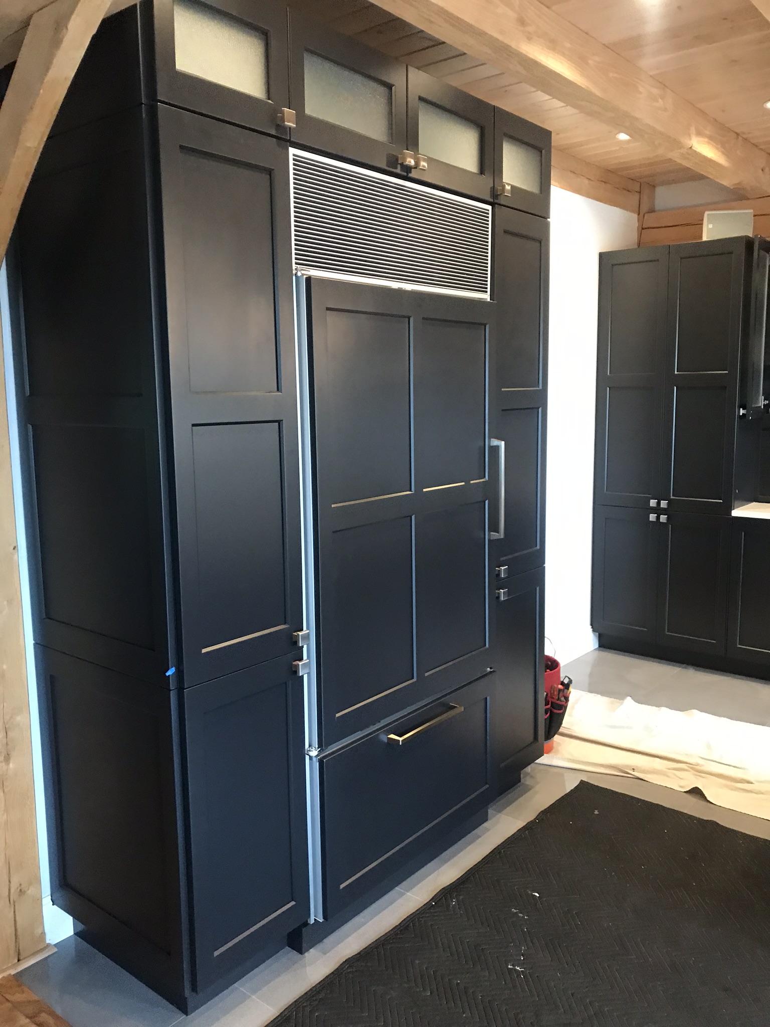 Tall custom black cabinetry surrounding the refrigerator