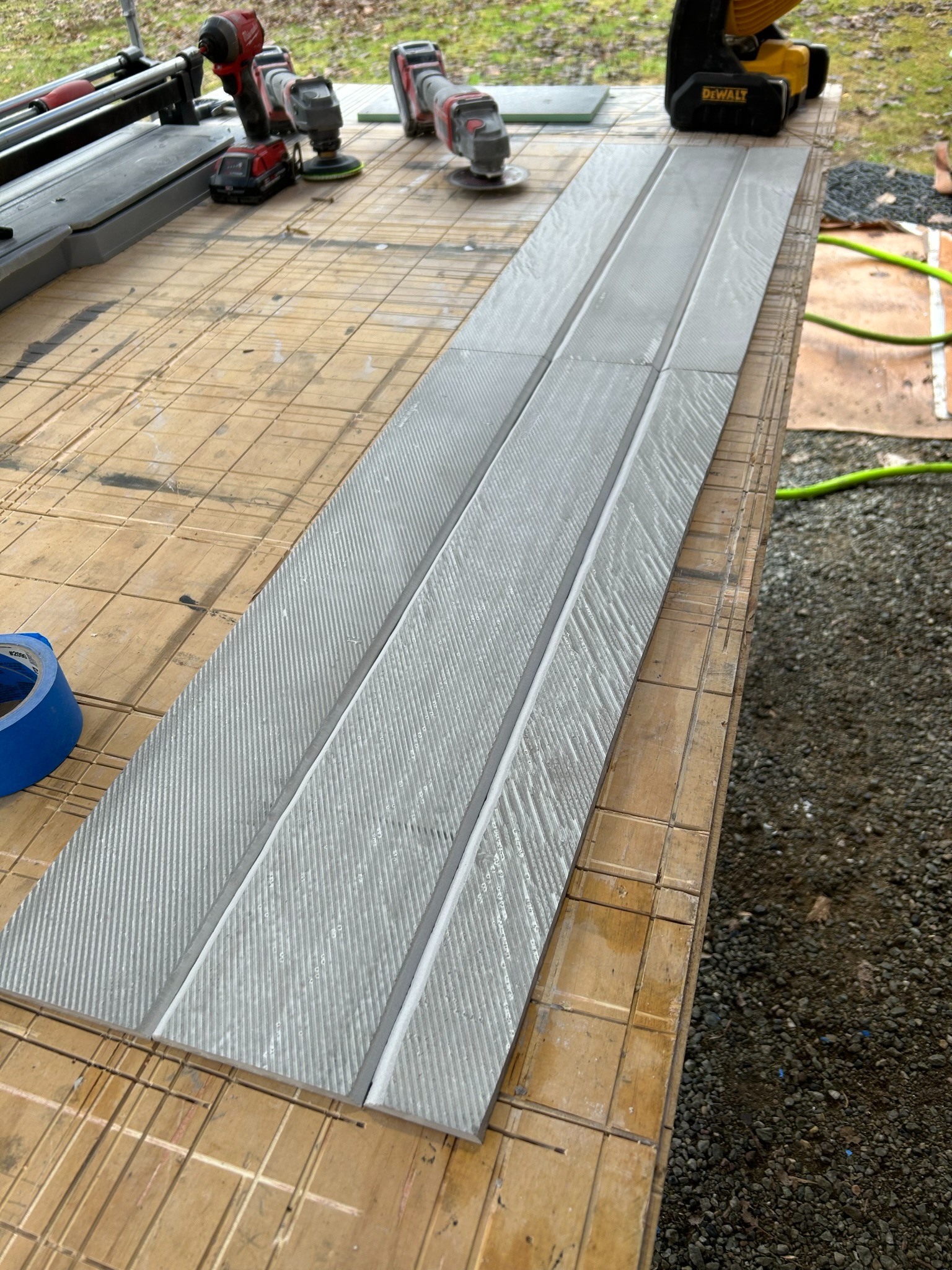 Large-format gray shower tiles being cut outdoors