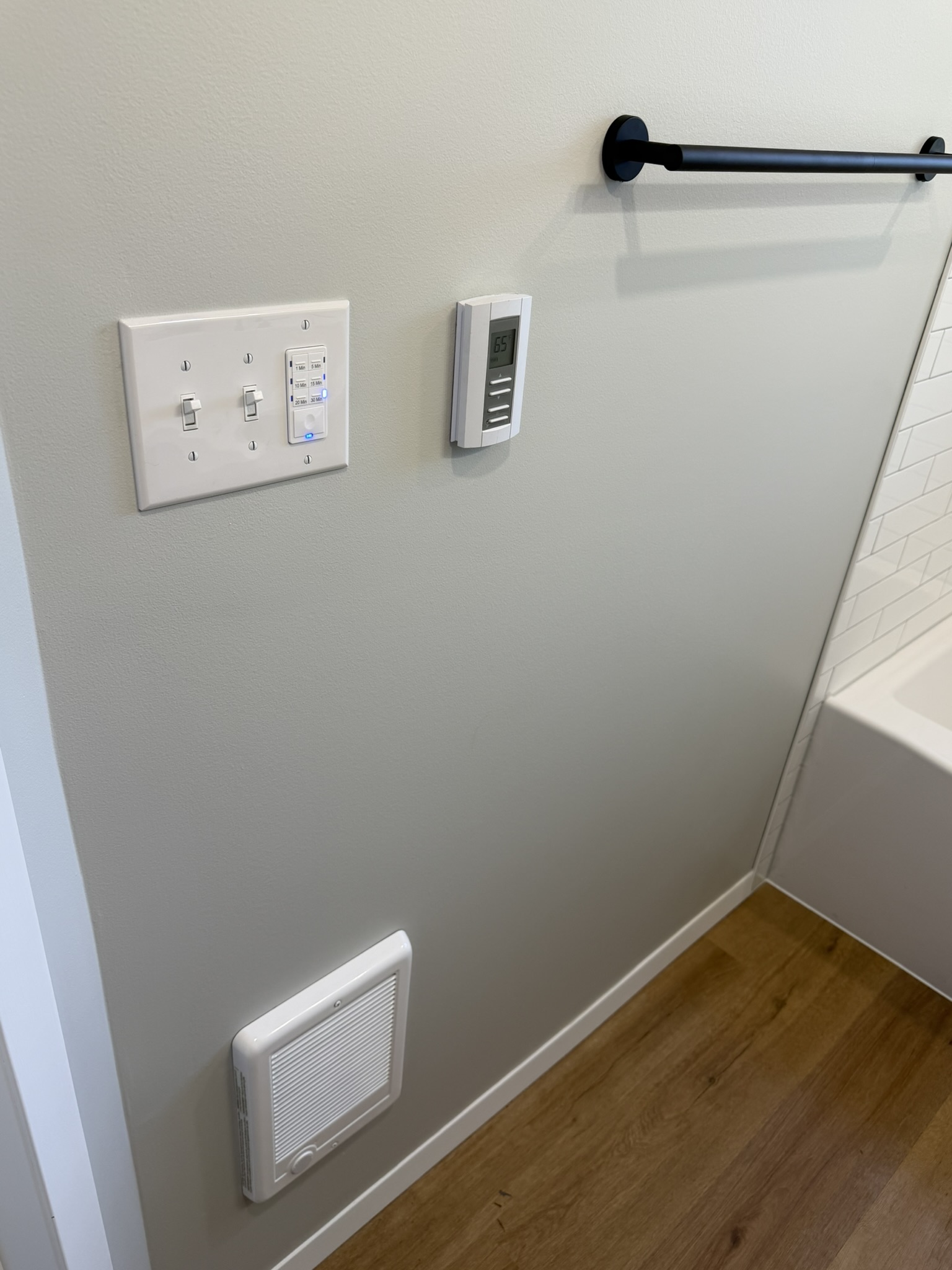 Finished bathroom wall with black towel bar and updated controls